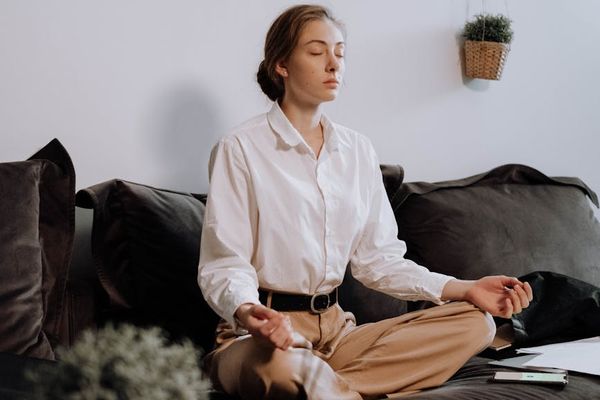 Person sitting in meditation with peaceful expression and soft light.