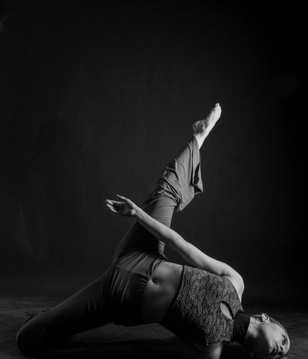 Woman performing a graceful yoga balance in a dark studio.